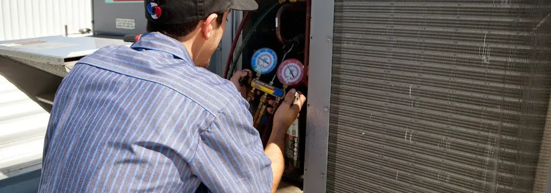 HVAC technician servicing a condenser unit in Countryside